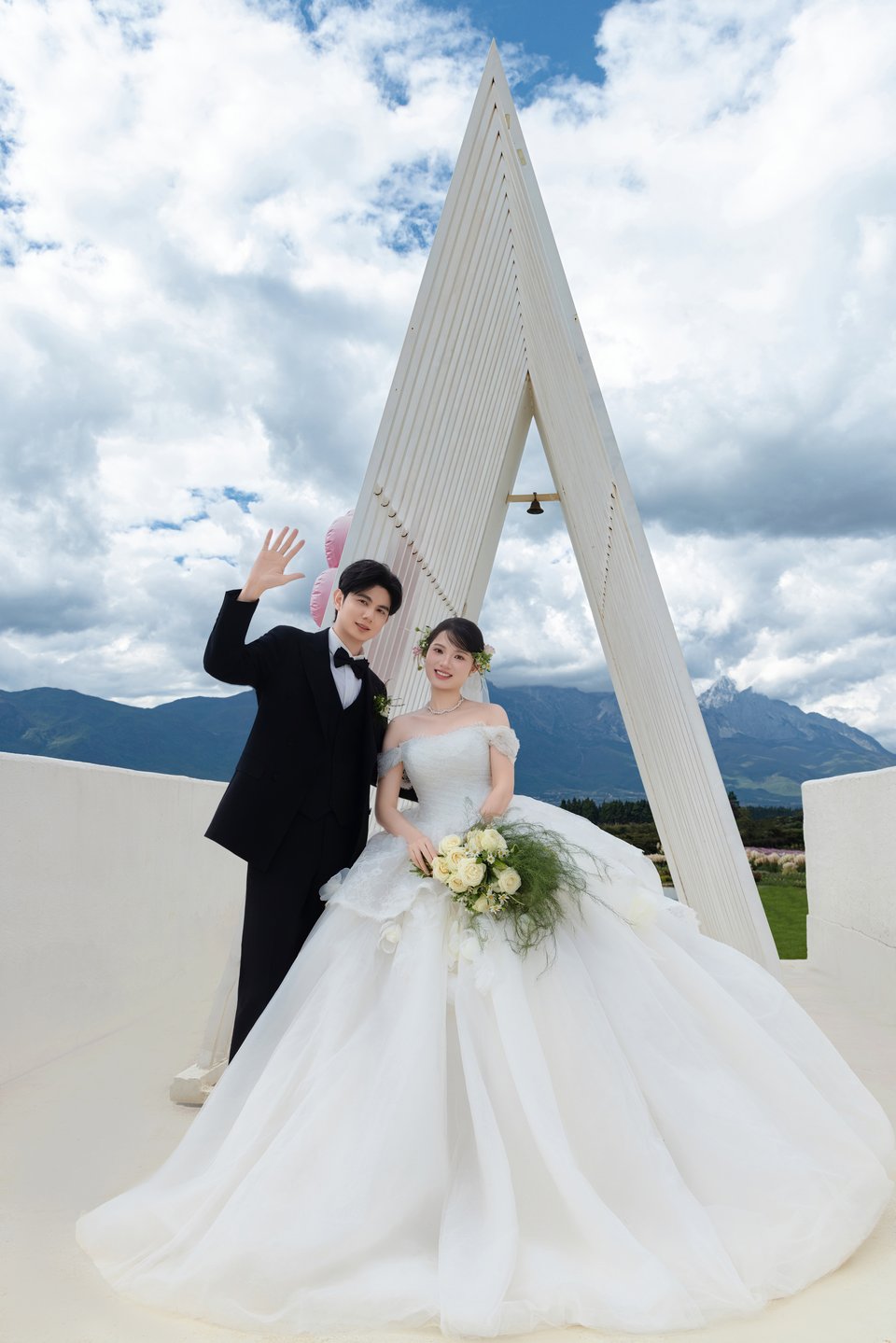 潘旖媚与李俊显身着婚纱礼服，在白色礼堂前携手挥手
